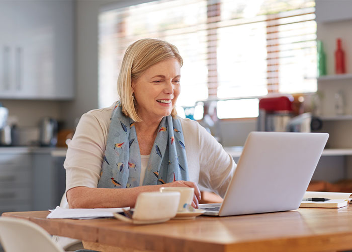 Woman smiling while working on her laptop.